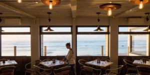 View across Newquay Harbour with fishing boats on the water and sandy shore beyond, capturing the harbourside setting near The Beach hut.